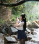 A woman in a school uniform standing in a stream.