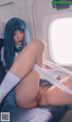 A woman with blue hair is sitting on an airplane.